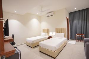 a hotel room with two beds and a television at Hotel Jubilee Park- Kondapur in Hyderabad