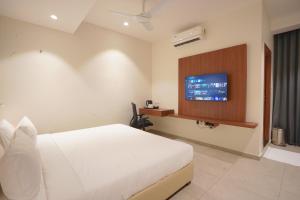 a bedroom with a white bed and a flat screen tv at Hotel Jubilee Park- Kondapur in Hyderabad