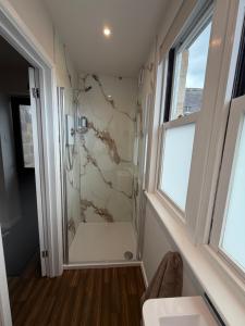 a bathroom with a shower and a sink and a window at Little Fairfield in Ashover +4 photos