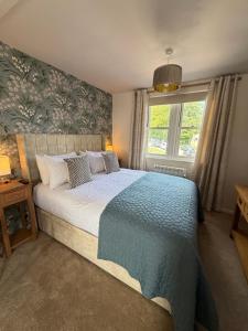 a bedroom with a bed with a blue blanket and a window at Little Fairfield in Ashover