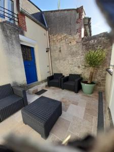 a patio with three chairs and a blue door at Studio in Isigny-sur-Mer