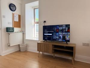 a living room with a flat screen tv on a wooden entertainment center at The Rock House in Cobh