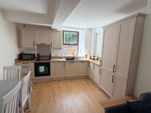 a large kitchen with white cabinets and a window at The Rock House in Cobh