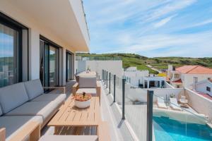 a balcony with a couch and a swimming pool at Beach Villa with ocean view in Lourinhã