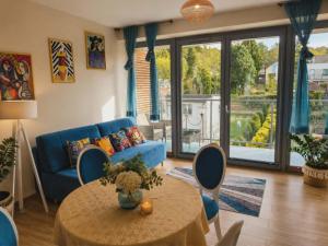 a living room with a blue couch and a table at Artystyczny Picasso apartament z widokiem na jezioro i tarasem in Charzykowy +1 photo