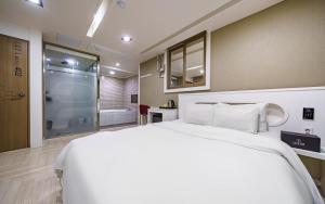 a bedroom with a large white bed and a bathroom at 자자호텔 in Goseong +3 photos