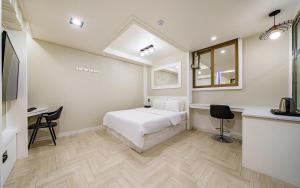 a bedroom with a bed and a desk and a window at 자자호텔 in Goseong