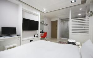 a white bedroom with a large bed and a tv at 자자호텔 in Goseong