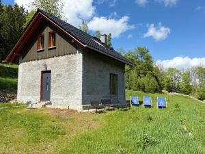 a small building with two blue chairs in a field at Agroturystyka Monte Luna - Domki in Czarnów +11 photos