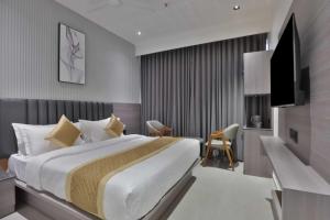 a hotel room with a bed and a television at Hotel Sunshine Suites IGI Airport in New Delhi