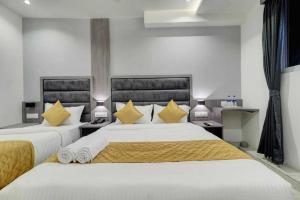 a bedroom with two beds with yellow pillows at Hotel Sunshine Suites IGI Airport in New Delhi