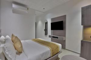 a white bedroom with a bed and a television at Hotel Sunshine Suites IGI Airport in New Delhi +18 photos