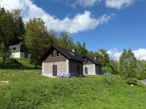 a house on a hill with chairs in a field at Agroturystyka Monte Luna - domki in Czarnów