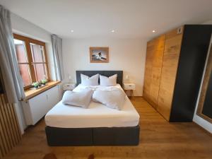 a bedroom with a bed with white sheets and pillows at Allgäuer Ferienwohnung mit Balkon, Bergblick und Wallbox in Rettenberg
