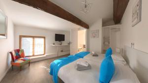 a bedroom with two beds with blue sheets and a chair at Maison M Bed and Breakfast in Alignan-du-Vent