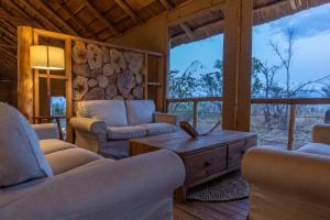 a living room with two couches and a wooden table at Kidepo Wilderness Lodge in Loitanit +28 photos
