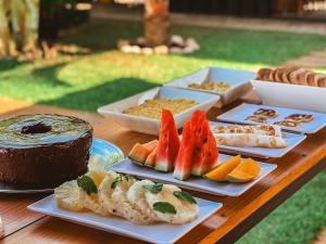 a wooden table with several plates of food on it at Eco Gostoso in São Miguel do Gostoso