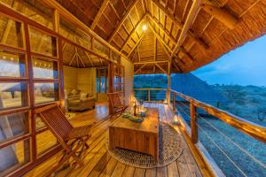a cabin with a table and chairs on a balcony at Kidepo Wilderness Lodge in Loitanit