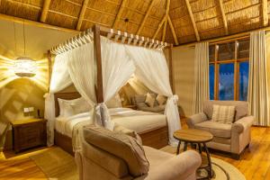 a bedroom with a canopy bed and a couch and chairs at Kidepo Wilderness Lodge in Loitanit