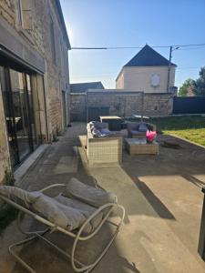 a patio with a chair and a couch and a table at Chambre des baumes in Chablis