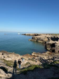 a couple of people walking on the rocks near the water at JV Country in Polignano a Mare +6 photos