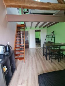 a room with a loft with a table and a staircase at Chambre des baumes in Chablis +5 photos