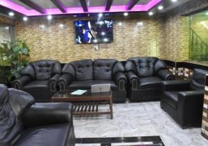 a living room with black leather couches and a table at Mughal E Azam Hotel in Murree
