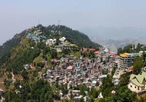 a village on a hill with houses and buildings at Mughal E Azam Hotel in Murree