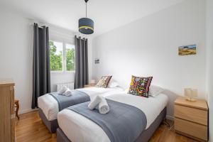 a bedroom with two beds and a window at L'Instant Arradon - Pointe & sentiers côtiers in Arradon