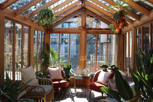 a conservatory with chairs and plants and windows at The Mandrake in London