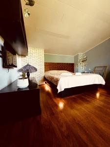 a bedroom with a large bed and a wooden floor at Shin Boutique Hotel with Mini Golf Terrace in Buriaki
