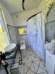 a bathroom with a toilet and a shower curtain at Shin Boutique Hotel with Mini Golf Terrace in Buriaki