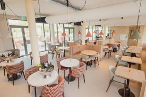 an empty restaurant with tables and chairs and windows at Hotel Riet I Kloeg Collection in Koudekerke