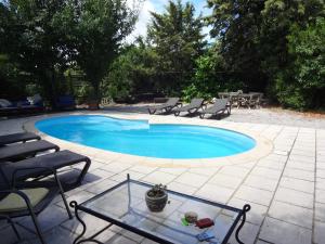 a swimming pool with chairs and a table in a yard at Bergerie L'Occitane in La Caunette