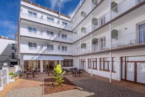 an apartment building with a courtyard with tables and chairs at Hotel GHT Simeon in Tossa de Mar