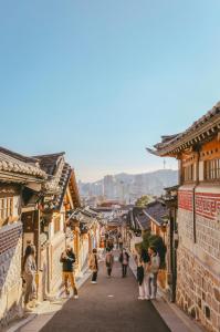 a group of people walking down a street in an old town at Nakwon Stay 3-Min Walk to Anguk & Jongno 3-ga Stations in Seoul