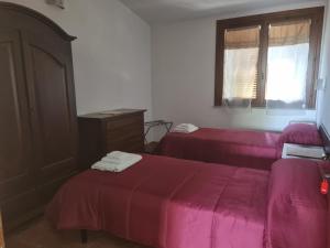 a room with two beds with pink sheets and a window at Agriturismo Punta Su Cunventu in Narcao