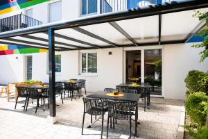 a patio with tables and chairs under awning at SHOME Hotel Graz I Self-Check-In I Free Parking in Graz