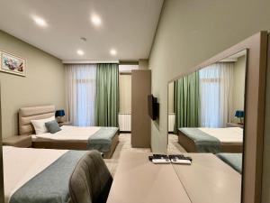 a hotel room with two beds and a television at Aurora Hotel Batumi in Batumi