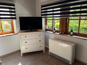 a room with a dresser with a tv and windows at Ferienwohnung Raschke in Fehmarnsund