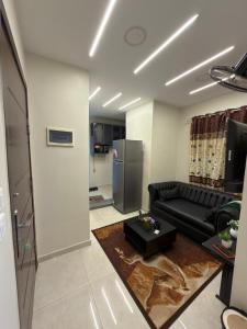a living room with a black couch and a refrigerator at شقة فندقية غرفة واحدة in Mansoura