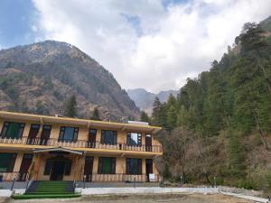 a large building with a balcony in front of a mountain at Pratham Place in Kasol