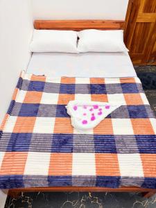 a bed with a blue and orange striped blanket and shoes at TJ Signature Spaces in Point Pedro