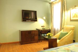 バンガロールにあるjuSTa MG Roadのベッド、テレビ、椅子が備わる客室です。