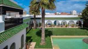 anterior view of a building with a swimming pool and palm trees at Villa NoYa in Oualidia