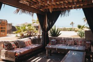 a porch with a couch and a table and palm trees at Surfiscamp Dakhla in Dakhla