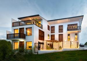 a white house with balconies and a yard at Amaru Suites Salento - Apartamentos con Jacuzzi y Vistas al Bosque in Salento
