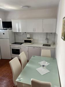 a kitchen with a table and white cabinets at Apartments Neda in Primošten