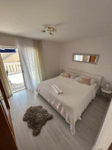 a bedroom with a large white bed and a window at Apartments Neda in Primošten