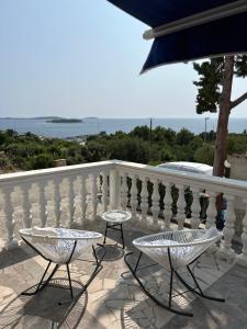 two chairs and tables on a balcony overlooking the ocean at Apartments Neda in Primošten